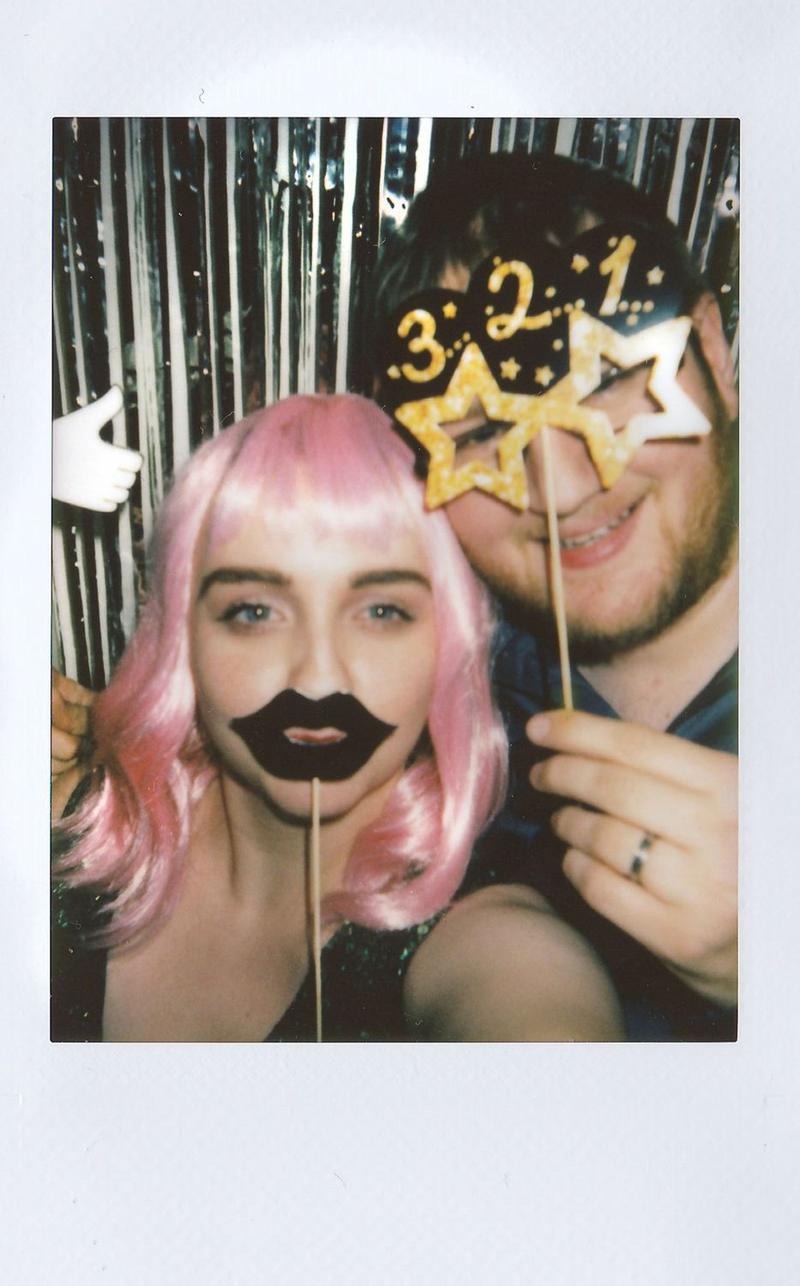 Instant print of a couple posing with mustache and star-glasses props
