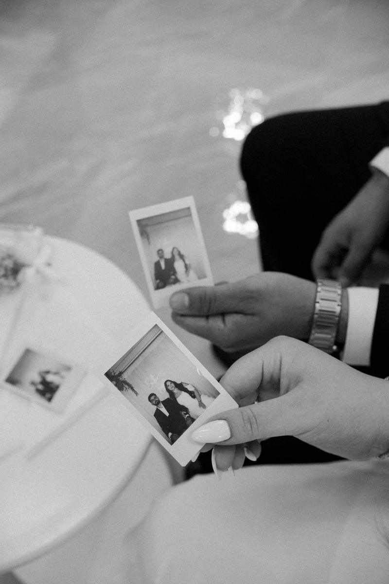 Bride and groom holding instant prints at their wedding reception